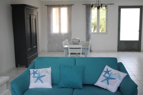 Canapé turquoise avec coussins étoile de mer dans le lumineux salon de la maison d'hôtes Sylvie CAMBON, Montséret