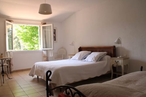 Chambre lumineuse au gîte Sylvie Cambon à Montséret avec lit en bois, draps blancs et vue sur le jardin