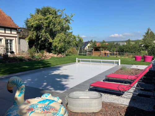 Heated outdoor swimming pool and wooden terrage at Le Clos d’Azel holiday rental in Flexbourg.