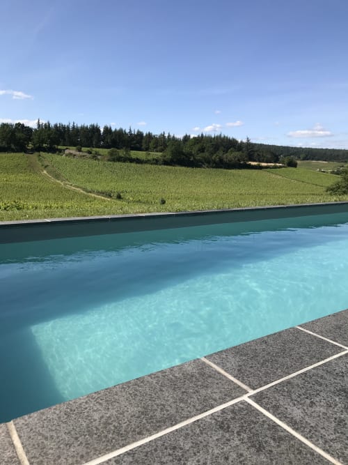Turquoise swimming pool overlooking vineyards and rolling green fields at Les Maisons de Chamirey in Mercurey, France