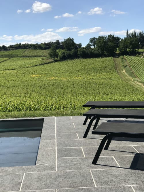 View from terrace at Les Maisons de Chamirey overlooking Mercurey vineyards with picnic table and loungers under blue sky