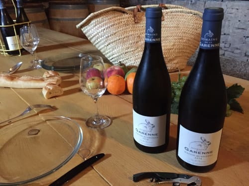 Wine tasting table at Domaine de Garenne with bottles, glasses, bread, and fresh fruits in Mercurey