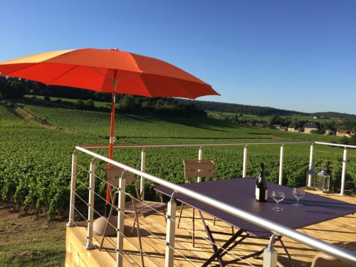 Red umbrella shading a table on wooden deck overlooking Mercurey vineyards at Les Maisons de Chamirey, Burgundy France