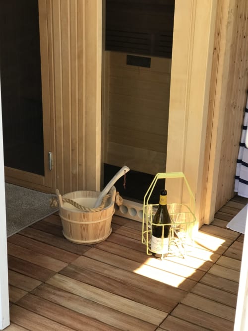 Sauna entrance at Les Maisons de Chamirey with wooden bucket, ladle, wine bottle holder, and wooden flooring in Mercurey