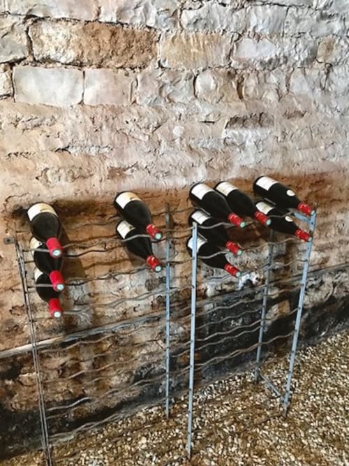 Wine bottle holders mounted on rustic stone wall at Les Maisons de Chamirey, Mercurey vineyard property