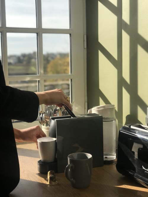 Person using Nespresso machine at window overlooking Mercurey vineyards, Les Maisons de Chamirey