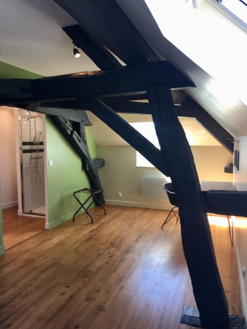Loft-style cottage room at Les Maisons de Chamirey with exposed beams, wooden floors, green accent wall, and modern amenities