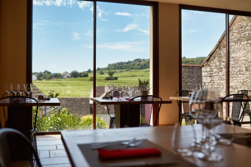 Elegant dining room at Les Maisons de Chamirey with vineyard views, set tables, and countryside landscape in Mercurey,