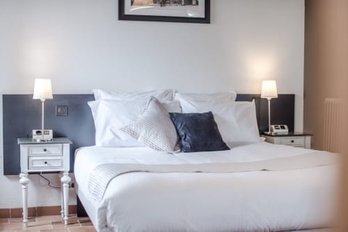 Modernes Schlafzimmer im B&B Le Pignié in Lescure-d'Albigeois mit weißer Bettwäsche, dunklem Kopfteil und eleganten Nachttischen
