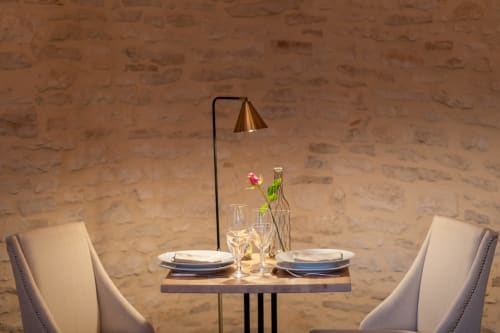 Mise en place intime au Clos Saint Jacques : deux fauteuils crème, table dressée, lampadaire en laiton et composition florale