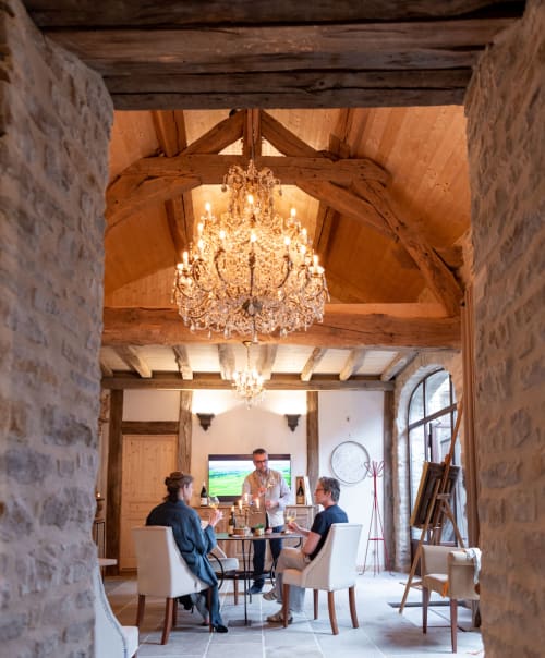 Elegantes Esszimmer des Clos Saint Jacques B&B in Meursault mit freiliegenden Holzbalken, Kristallleuchtern und speisenden Gästen