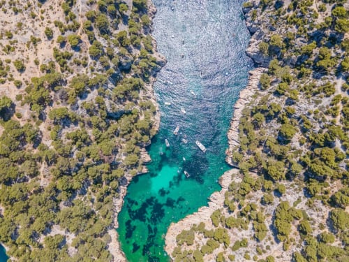 Aerial view of turquoise cove surrounded by pine forests near Provence Km28 in Gordes, France