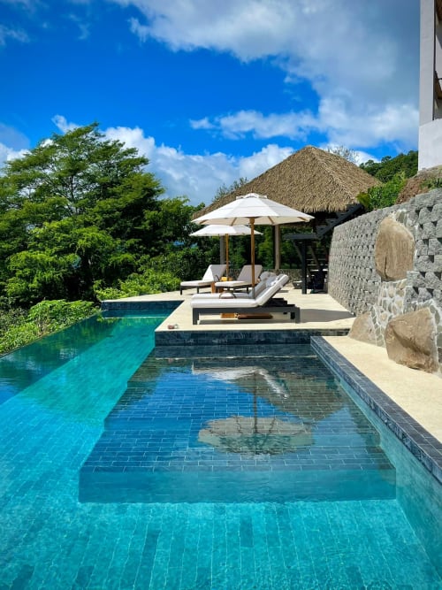 Piscine à débordement luxueuse à Organica Yoga Shelter à Puntarenas avec eaux turquoise, transats, parasols blancs et vue sur l'océan