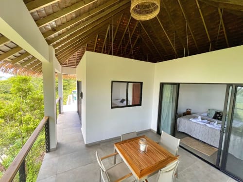 Terrasse exclusive du lodge Organica Yoga Shelter avec vue océan, table de salle à manger en bois et accès à la chambre à Paquera