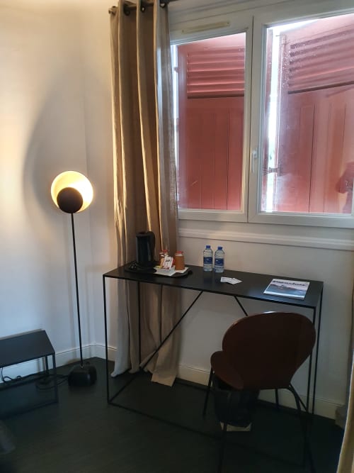 Bureau de la Suite Junior avec chaise, lampadaire et bouteilles d'eau à l'Hôtel Au Bon Coin à Biarritz, avec vue sur la ville