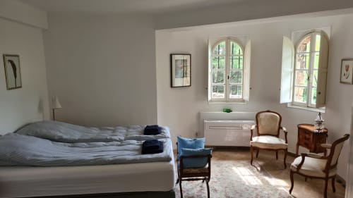 Bright bedroom at La Sentinelle B&B in Les Arcs, featuring a bed, antique chairs, arched windows, and mountain views