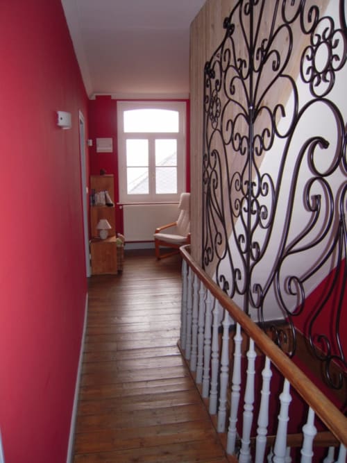 Couloir aux murs roses, parquet, et élégante rampe en fer forgé à La ferme de l'Ostrevent
