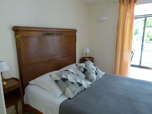Elegant bedroom at Villa Thébaïde with wooden headboard, patterned pillows, and garden view through terrace doors