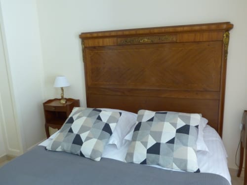 Bedroom at Villa Thébaïde with wooden headboard, patterned pillows, and bedside lamp in Laudun L'Ardoise