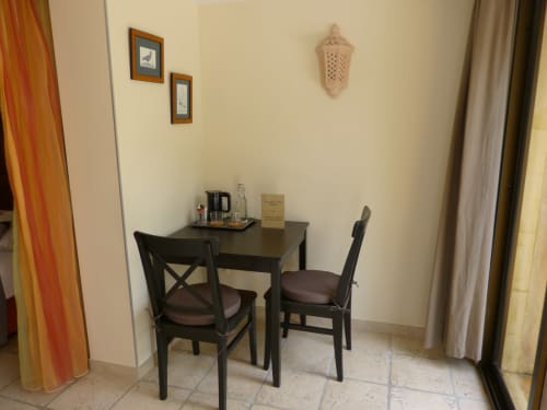 Black desk and chairs in hotel room at Villa Thébaïde, Laudun L'Ardoise, with coffee facilities and wall decor