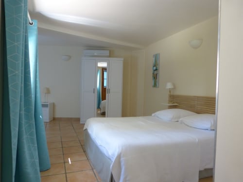 Spacious bedroom at Villa Thébaïde cottage in Laudun, France, with double bed, mirrored wardrobe, and garden view