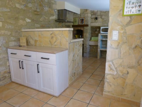 Fully equipped kitchen in L'Oliveraie Cottage at Villa Thébaïde, Laudun L'Ardoise, with white cabinetry and stone walls