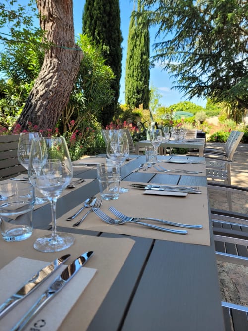 Elegante Außengastronomie in der Villa Thébaïde mit gedecktem Tisch, Weingläsern und mediterranem Garten in Laudun