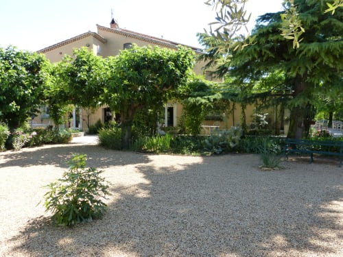 Innenhof der Villa Thébaïde mit Kiesgartenanlage, Kletterpflanzen und traditioneller Schieferarchitektur in Laudun L'Ardoise