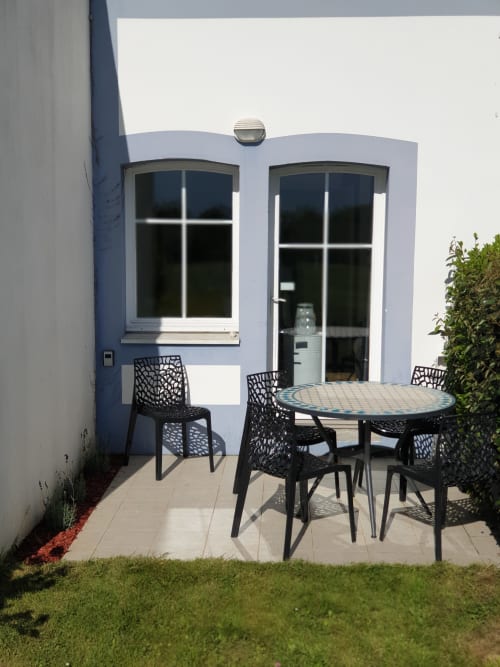 Terrasse moderne avec table à manger et chaises noires à la location Locmaria, Belle Île en Mer