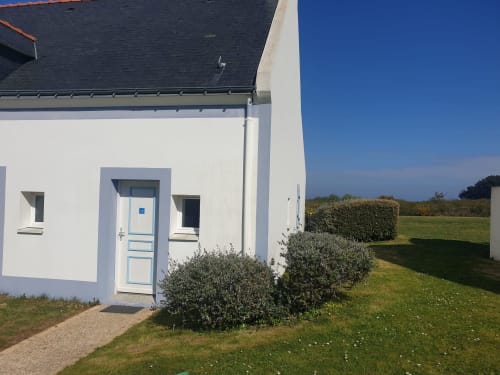 Petit cottage blanc avec porte bleue à Loc'Maria, Belle Île en Mer, jardin soigné et vue sur mer