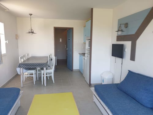 Appartement de vacances à Locmaria avec table à manger, canapés bleus, TV et kitchenette à Belle Île en Mer
