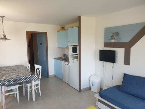 Studio à la résidence Locmaria avec kitchenette, coin repas, télévision et canapé bleu sur Belle Île en Mer