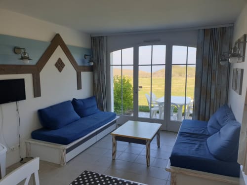 Salon lumineux avec assises bleues, vue mer par grandes fenêtres, location vacances Belle Île en Mer