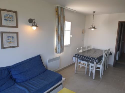 Lumineux séjour avec canapé bleu, table à manger, vue sur la mer et décoration côtière à Locmaria Belle-Île-en-Mer