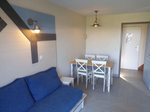Appartement moderne à Locmaria avec canapé bleu, table à manger et chaises blanches dans l'espace de vie