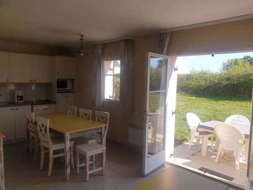 Salle à manger lumineuse avec cuisine dans l'appartement de Locmaria, ouvrant sur terrasse de jardin avec chaises blanches