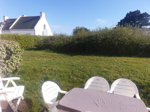 Chaises Adirondack blanches surplombant un jardin luxuriant à Loc'Maria, location de vacances à Belle Île en Mer