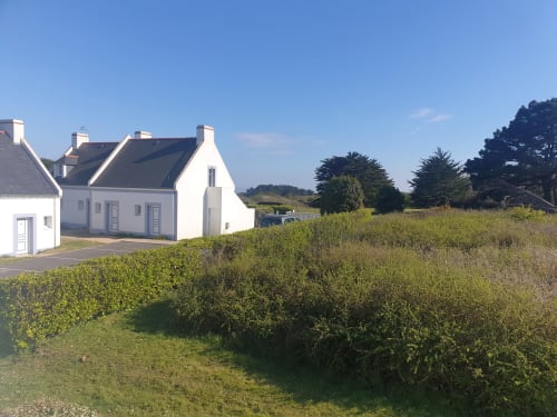 Petit appartement blanc avec vue sur jardin à Loc'Maria, Belle Île en Mer, entouré de verdure luxuriante