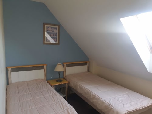 Deux lits jumeaux dans une chambre mansardée lumineuse aux murs bleus et puits de lumière à l'appartement Locmaria