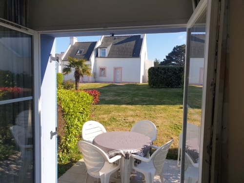 Table et chaises blanches de patio surplombant un jardin soigné à la location de vacances Locmaria Belle Île en Mer
