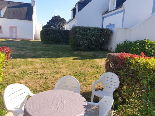 Espace de détente au jardin de Loc'Maria Belle Île en Mer avec chaises blanches, table ronde et aménagement paysager coloré