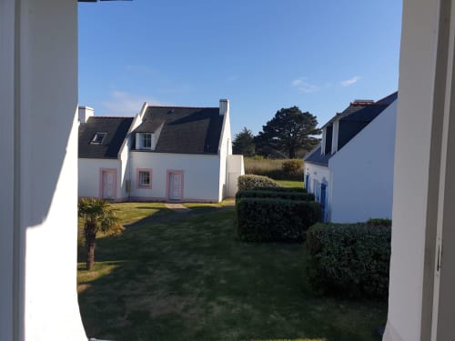 Maison blanchie aux accents roses et toit sombre à Locations Loc'Maria, Belle Île en Mer, entourée de jardins paysagés