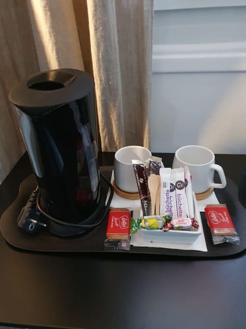 Plateau de bienvenue de la Junior Suite de l'Hôtel Au Bon Coin avec cafetière, tasses blanches et services gratuits à Biarritz.