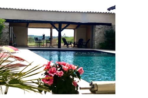 Le Pignié BnB pool area in Lescure-d'Albigeois with loungers, pink flowers, and countryside views