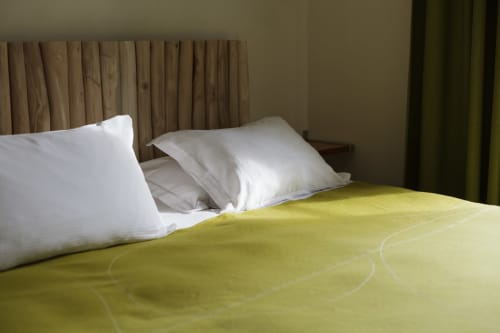 Luxe hotelbed met witte kussens en gele plaid in Moulin Renaudiots in Autun, kamer Saint André