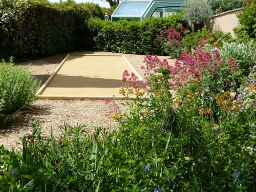 Garten der Villa Thébaïde mit rosa Blüten, Kiesweg und Bouleplatz in Laudun l'Ardoise, Frankreich