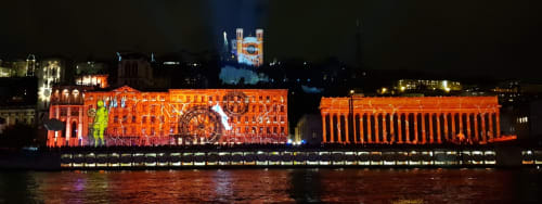 Bâtiments orangés illuminés se reflétant dans l'eau la nuit avec une cathédrale bleue en arrière-plan