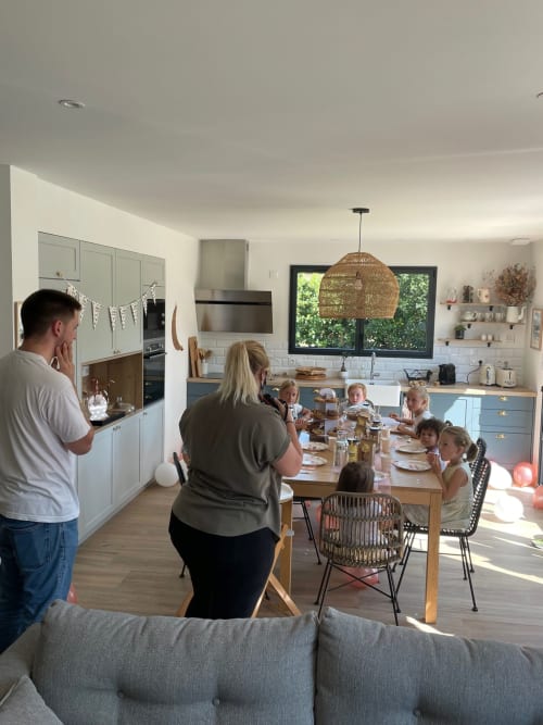 Réunion familiale dans la cuisine-salle à manger moderne du Manoir de la Nogrie, Val d'Izé, baignée de lumière naturelle