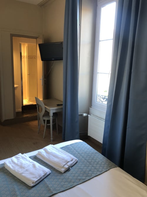 Hôtel Maison Richet double bedroom in Les Sables-d'Olonne with TV, desk, towels, and balcony door