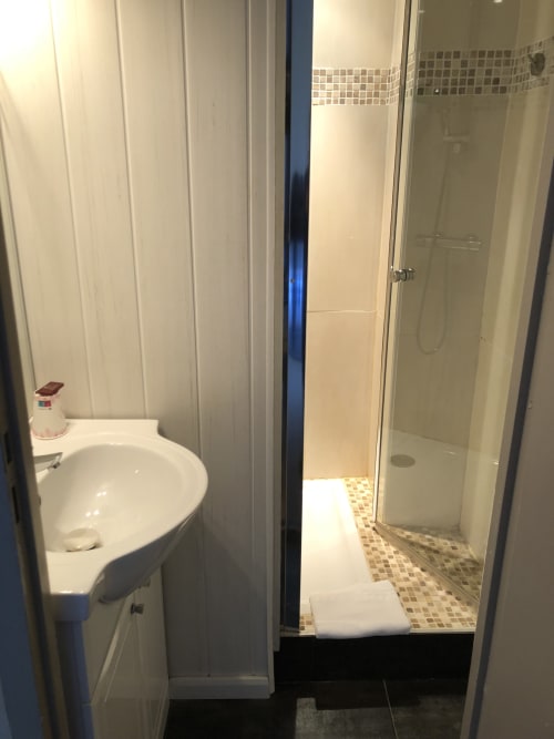 Modern bathroom with corner sink and glass shower enclosure at Hôtel Maison Richet, Les Sables-d'Olonne